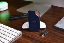 Close-up of a desk setup featuring a SanDisk SSD, keyboard, and USB drive, highlighting modern technology.