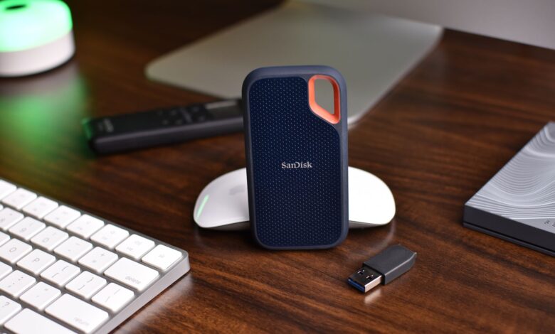 Close-up of a desk setup featuring a SanDisk SSD, keyboard, and USB drive, highlighting modern technology.