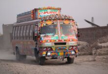 Colorful Pakistani truck driving on a dusty rural road in Punjab, showcasing traditional artwork.