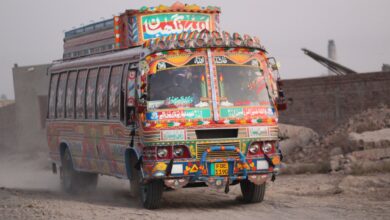 Colorful Pakistani truck driving on a dusty rural road in Punjab, showcasing traditional artwork.
