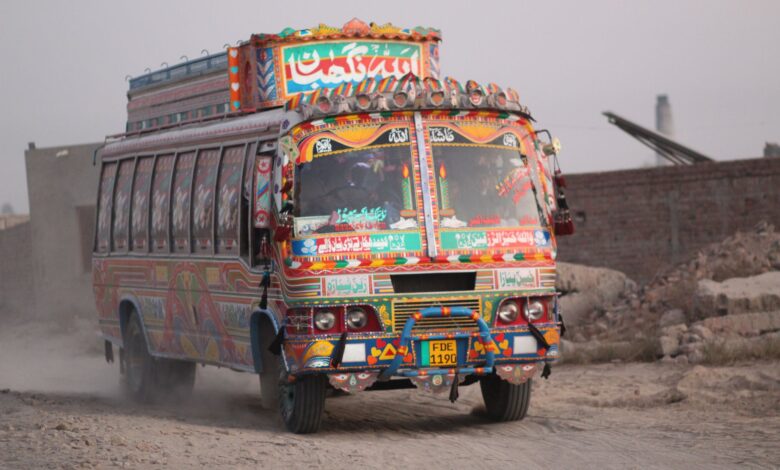 Colorful Pakistani truck driving on a dusty rural road in Punjab, showcasing traditional artwork.
