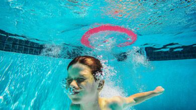 A child energetically plays underwater in a swimming pool, surrounded by bubbles and splashes.