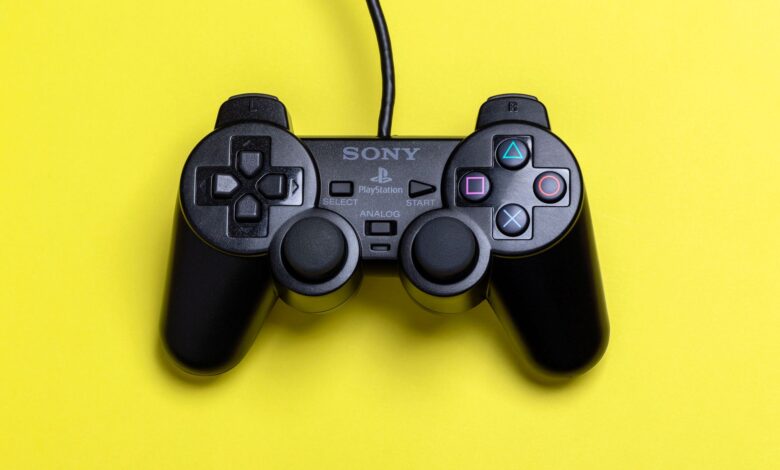 A close-up view of a black gaming controller set against a vibrant yellow background, highlighting modern gaming technology.