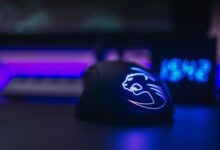 Close-up of an illuminated gaming mouse with LED lights on a dark desk setting.