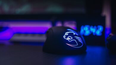Close-up of an illuminated gaming mouse with LED lights on a dark desk setting.