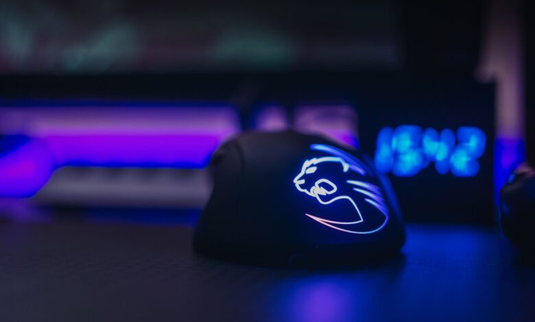 Close-up of an illuminated gaming mouse with LED lights on a dark desk setting.