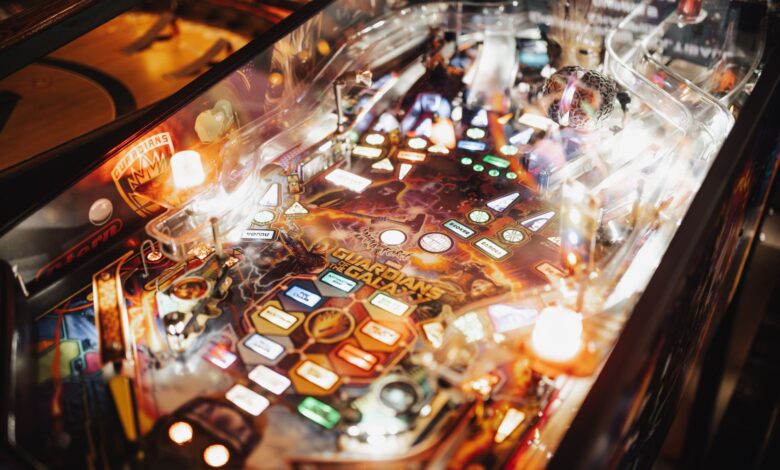 Colorful pinball machine in an arcade setting with bright lights and intricate design.