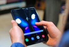 Close-up of hands holding a foldable smartphone showing a butterfly on the screen.