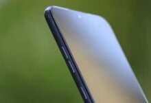 Detailed close-up of sleek smartphone edge with buttons against green background.