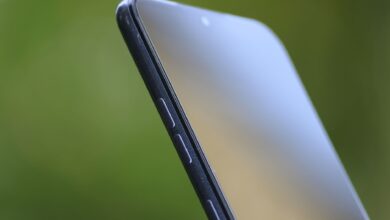 Detailed close-up of sleek smartphone edge with buttons against green background.