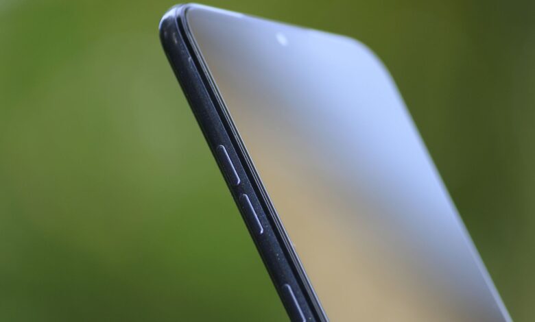 Detailed close-up of sleek smartphone edge with buttons against green background.
