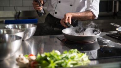 Chef prepares food in a sleek kitchen using a frying pan on an induction cooktop.