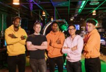 A confident and diverse group of friends standing in an arcade gaming environment.