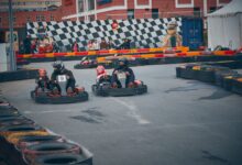 Thrilling outdoor go-kart race with competitors wearing helmets speeding on a track.