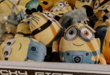 A collection of vibrant minion plush toys inside an arcade claw machine, perfect for entertainment.