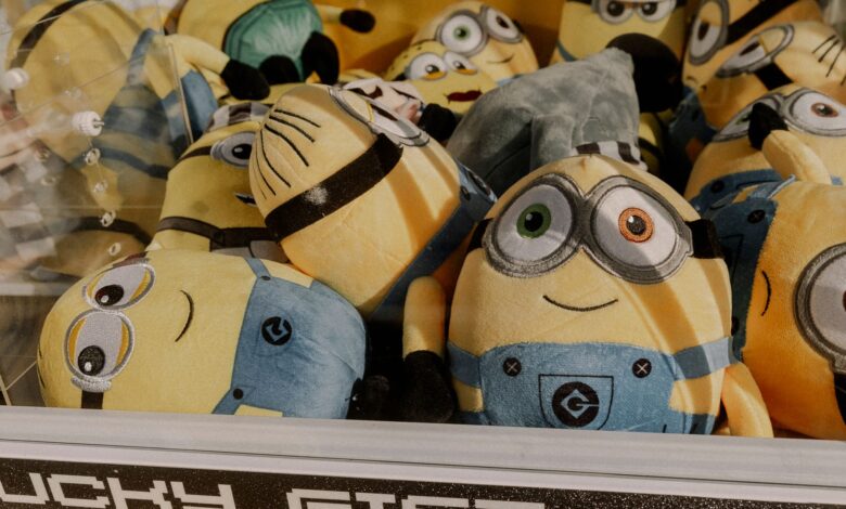 A collection of vibrant minion plush toys inside an arcade claw machine, perfect for entertainment.