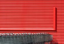 A vibrant red building facade with aligned metal shopping carts in front.