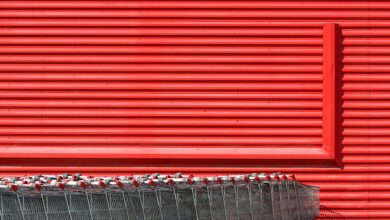 A vibrant red building facade with aligned metal shopping carts in front.