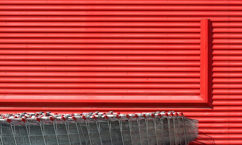 A vibrant red building facade with aligned metal shopping carts in front.