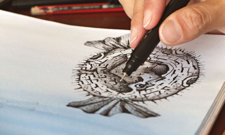 A person skillfully drawing a pufferfish illustration with fine details using a pen.