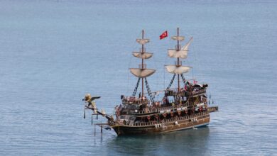 A historic pirate ship sails in clear waters under a sunny sky, adorned with a Turkish flag.