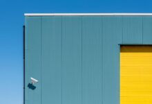 Simple architectural composition with a security camera on a colorful building facade.