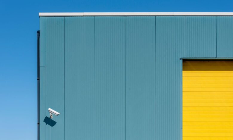 Simple architectural composition with a security camera on a colorful building facade.