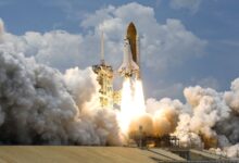 Witness the powerful launch of a space shuttle amidst massive clouds of smoke against a bright sky.