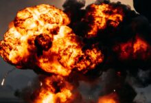 Intense explosion with fiery flames and dark smoke billowing skyward, showcasing dramatic impact.