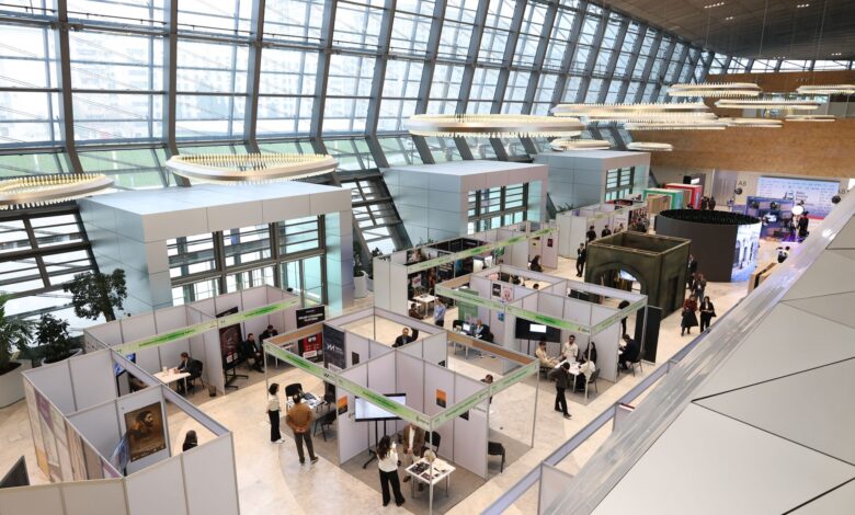 A bustling trade show exhibition inside a modern hall with people networking and exploring booths.