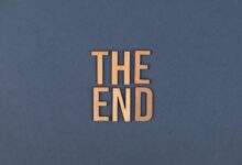 Wooden letters form 'The End' on a plain blue surface, ideal for concluding or finality themes.