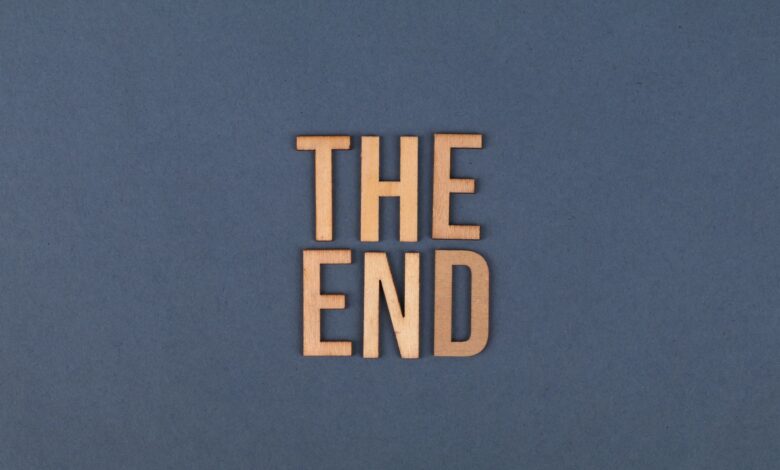 Wooden letters form 'The End' on a plain blue surface, ideal for concluding or finality themes.