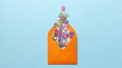 A vibrant collection of puzzle pieces spilling out of an orange envelope on a light blue background.