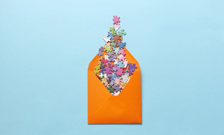 A vibrant collection of puzzle pieces spilling out of an orange envelope on a light blue background.