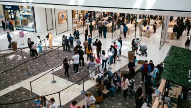A bustling shopping center with a large crowd queuing inside an Apple Store.