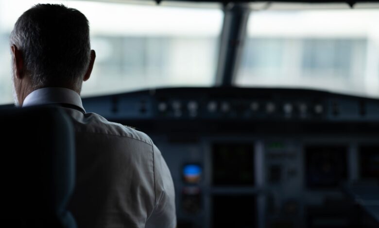 A focused view of an airline pilot in the cockpit, emphasizing responsibility and aviation control.