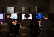 Three men focused on an intense PC gaming session in a modern esports arcade, enjoying teamwork and strategy.