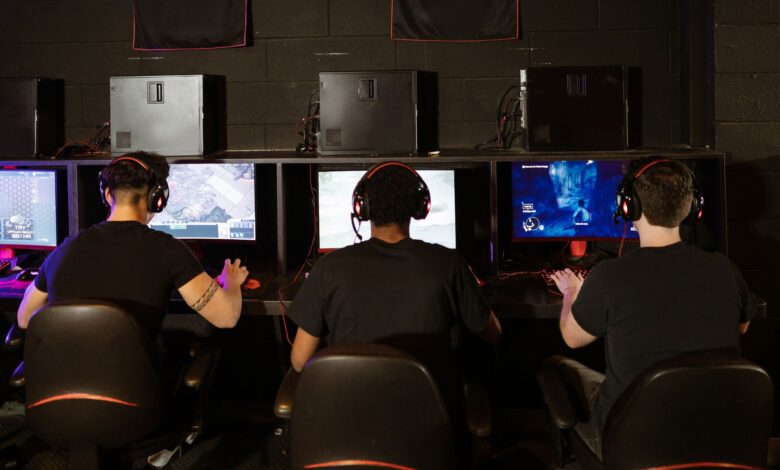 Three men focused on an intense PC gaming session in a modern esports arcade, enjoying teamwork and strategy.