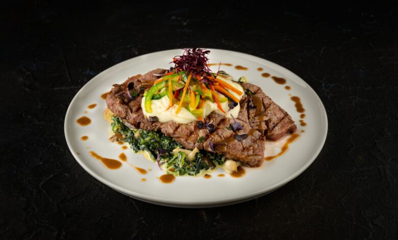 Savor the elegant presentation of a gourmet steak dish with fresh vegetable garnish and creamy sauce.