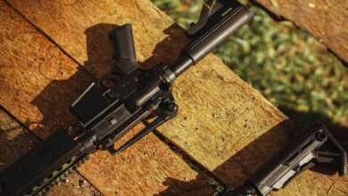 AR-style rifle displayed on wooden planks in natural light, showcasing tactical features.
