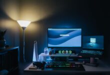 A stylish home office desk setup with dual monitors and ambient blue lighting.