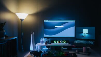 A stylish home office desk setup with dual monitors and ambient blue lighting.