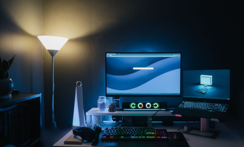 A stylish home office desk setup with dual monitors and ambient blue lighting.