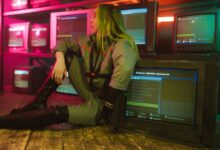 Woman in cyberpunk attire sits surrounded by vintage TVs in a neon-lit room, evoking retro-futuristic vibes.