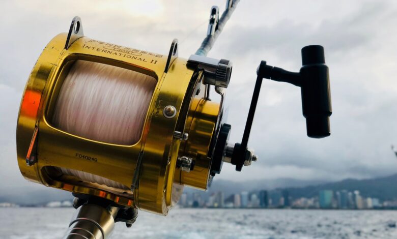 Close-up of a fishing rod and reel over the ocean with the Honolulu skyline in the background.