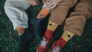 Two friends wearing playful socks sit closely on grass, showing comfort and friendship.
