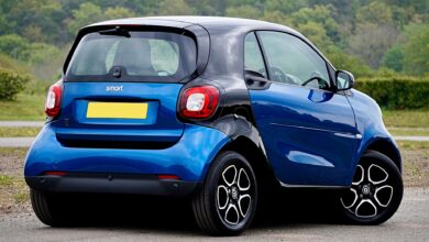 A blue Smart car parked in a scenic outdoor setting, showcasing modern design and compact size.