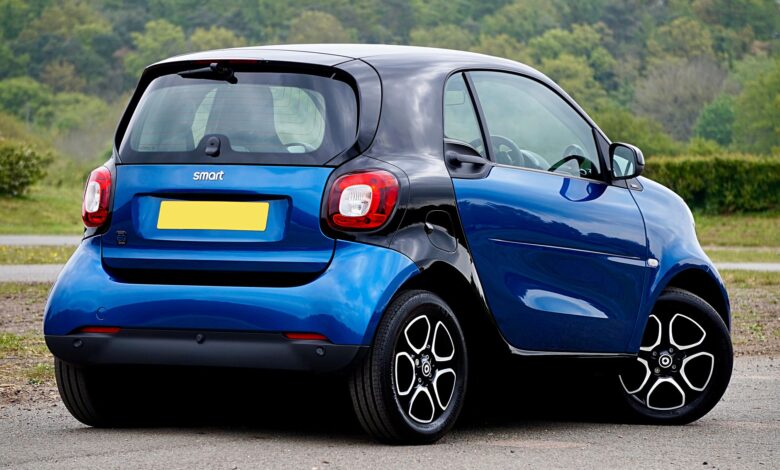 A blue Smart car parked in a scenic outdoor setting, showcasing modern design and compact size.