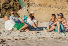 A group of friends relaxing and chatting on a beach during a sunny summer day.