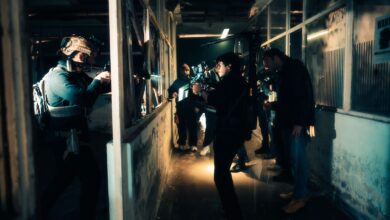 A cinematic scene capturing actors filming an intense action sequence in a dimly lit warehouse.